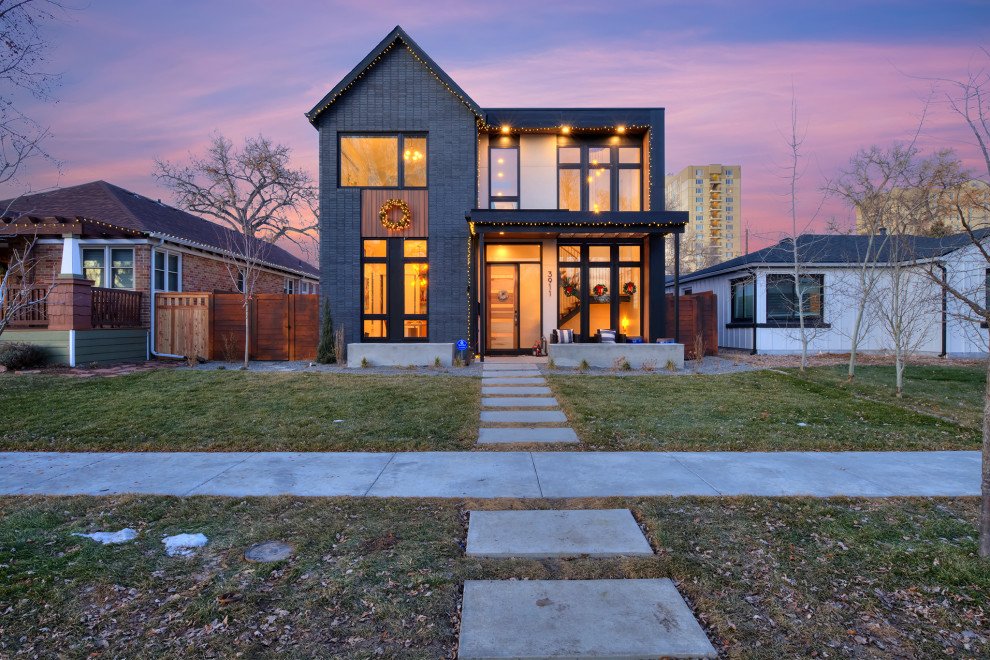 A Renovar-built two-story home at dusk, its siding painted deep charcoal with black window trim